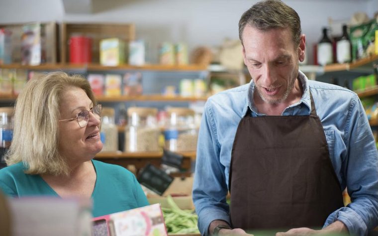 Un commesso consiglia una cliente in un negozio di alimentari